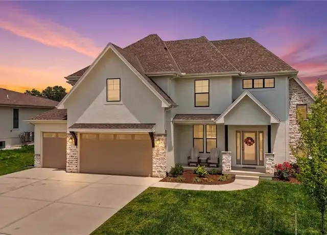 Residential Home in Grandview, Missouri Featuring a Three-car Garage, Concrete Driveway, Covered Front Porch, and Professionally Landscaped Front Yard at Sunset | Piermagic®